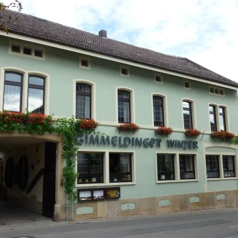 Ein schönes Gebäude mit grüner Fassade und Blumenbalkonen. Das Haus hat große Fenster und befindet sich in einer ruhigen Straße.