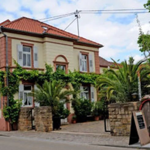 Ein charmantes Gebäude mit einer roten Dachfläche und schönen Pflanzen. Die Fassade ist geschmackvoll gestaltet und lädt zum Verweilen ein.