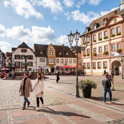 Ein schöner Platz mit historischen Gebäuden und bunten Fassaden. Paare und Menschen genießen einen sonnigen Tag im Freien.