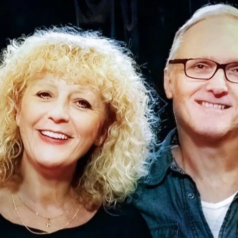 Ein lächelndes Paar steht freundlich nahe beieinander. Beide wirken glücklich und entspannt.