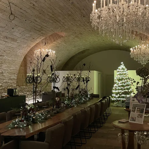 Ein weihnachtlich geschmückter Gewölbekeller mit beleuchtetem Weihnachtsbaum, der die festliche Atmosphäre unterstreicht.