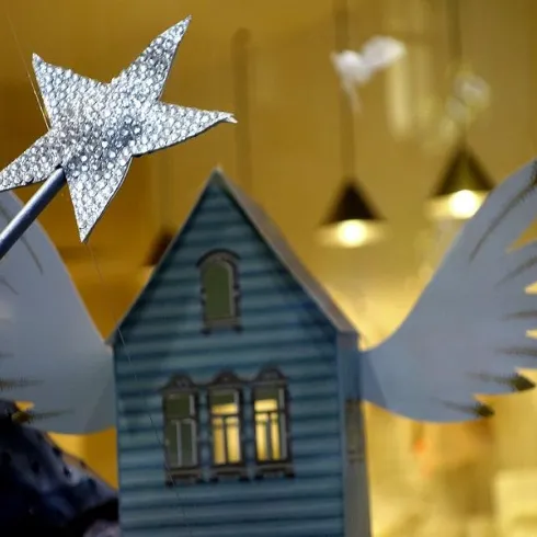 Ein geheimnisvolles Dekorationsstück mit einem blauen Haus und einem glitzernden Stern mit Flügeln. Die Szene vermittelt ein Gefühl von Fantasie und Magie.