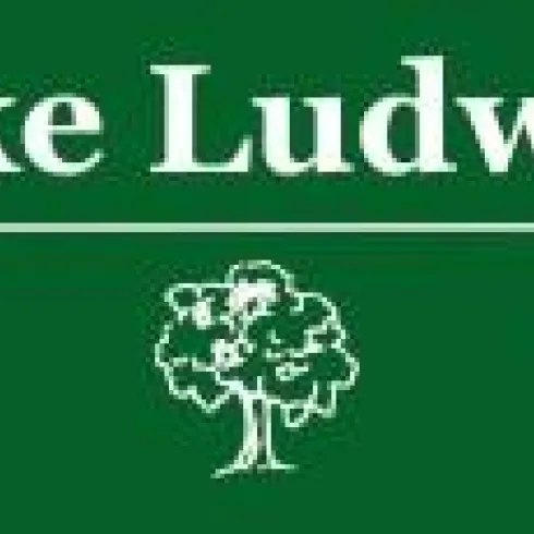 Ein Schild mit der Aufschrift "Waldschenke Ludwigsbrunnen" auf grünem Hintergrund. Darunter sind fünf Sterne und ein Baum-Symbol zu sehen.