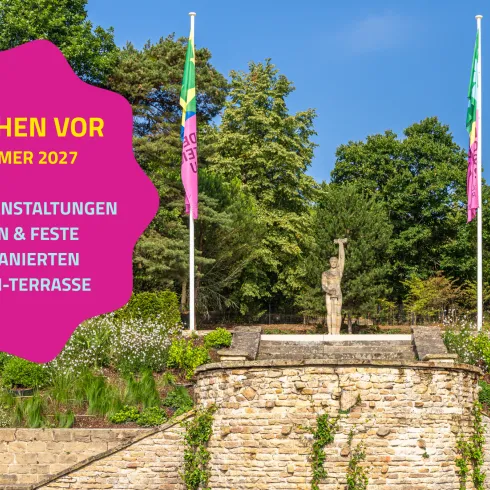 Ein schöner Garten mit einer Statue und bunten Fahnen. In der Mitte steht eine Werbung für Veranstaltungen im Sommer 2027.