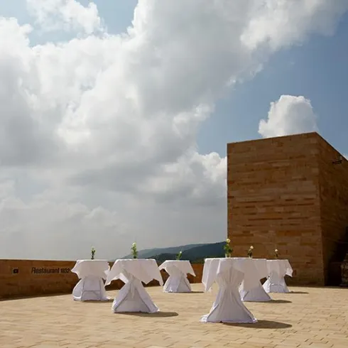 Eine Terrasse mit dekorierten Tischdecken und frischen Blumen. Der Himmel ist bewölkt und es gibt eine ruhige Atmosphäre.