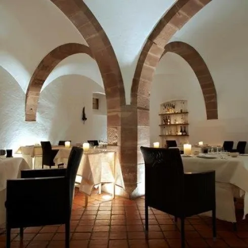 Ein elegantes Restaurant mit gewölbten Decken und sanfter Beleuchtung. Die Tische sind festlich gedeckt und schaffen eine gemütliche Atmosphäre.