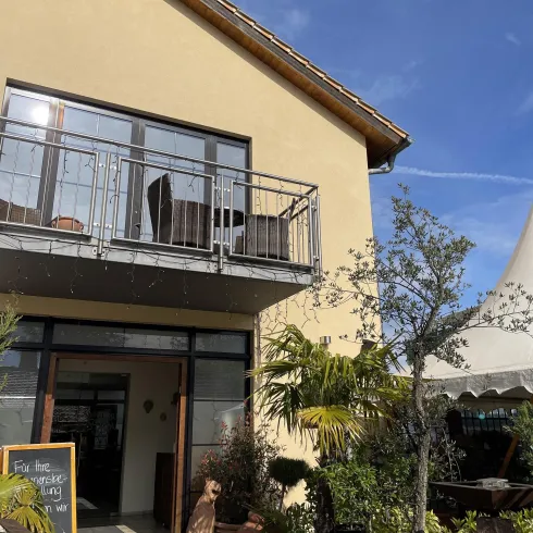 Ein schönes Gebäude mit einem Balkon und einer Terrasse. Umgeben von Pflanzen und einer einladenden Atmosphäre.