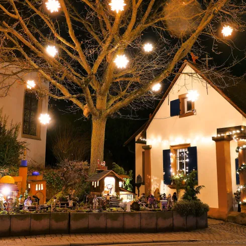 Ein festlich dekoriertes Haus mit Lichtern und einem geschmückten Baum. Die Atmosphäre ist gemütlich und einladend in der Nacht.