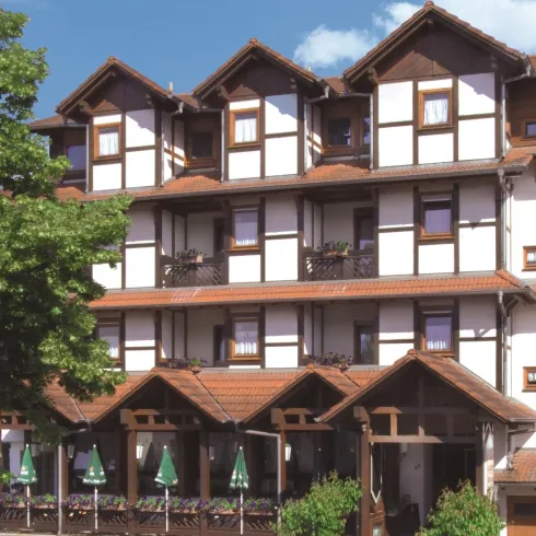 Ein traditionelles Fachwerkhaus mit mehreren Etagen. Die Fassade ist hell, mit Balkonen und einem überdachten Eingangsbereich.