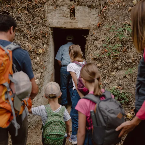 Eine Gruppe von Wanderern betritt eine Höhle. Sie tragen Rucksäcke und sehen neugierig aus.
