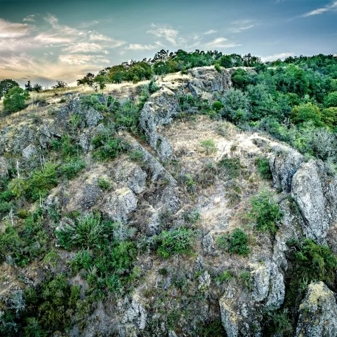 Eine beeindruckende Felsenlandschaft mit bewachsenen Hängen und einem klaren Himmel. Die Natur ist üppig und grün, ideal für Outdoor-Aktivitäten.