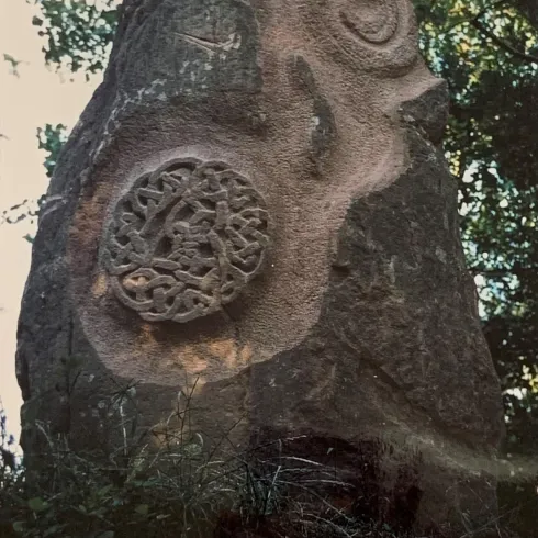 Ein großer Felsen mit kunstvollen Schnitzereien. Die Motive zeigen eine spiralförmige Figur und ein kreisförmiges Muster.