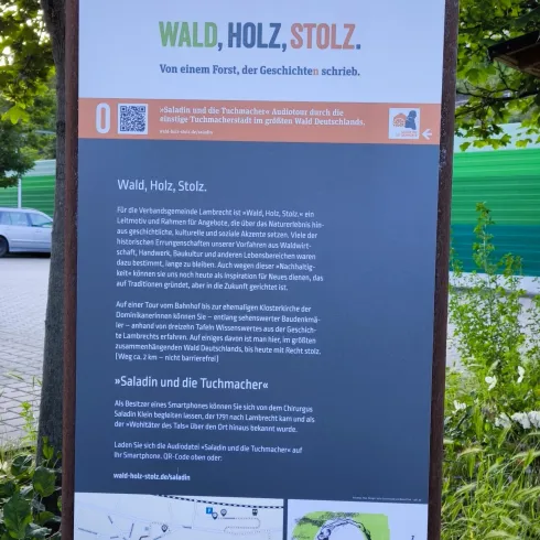Ein Informationsschild mit dem Titel „Wald, Holz, Stolz“. Es enthält Text über den Wald und Holz sowie eine Karte und eine Zeichnung.
