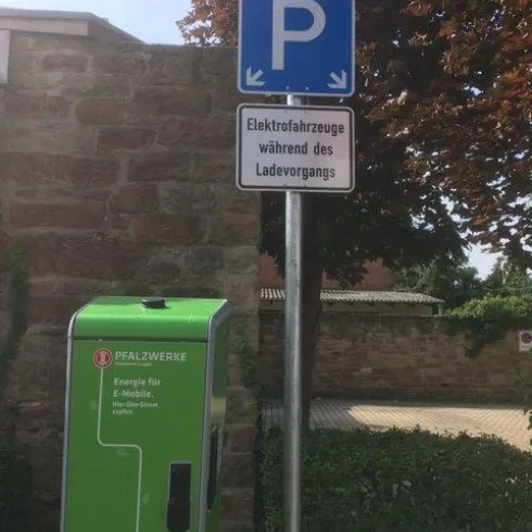 Eine Parkzone mit einem Schild für Elektrofahrzeuge. Neben dem Schild steht eine Ladestation für Elektroautos.