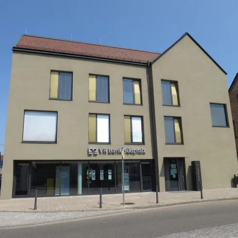 Ein modernes Gebäude mit einer einfachen Fassade und großen Fenstern. Es befindet sich an einer ruhigen Straße.