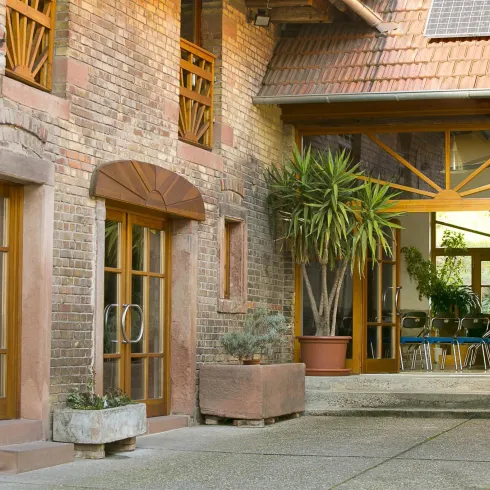 Ein gemütlicher Innenhof mit Holzfenstern und Pflanzen. Die Umgebung vermittelt ein einladendes und warmes Ambiente.