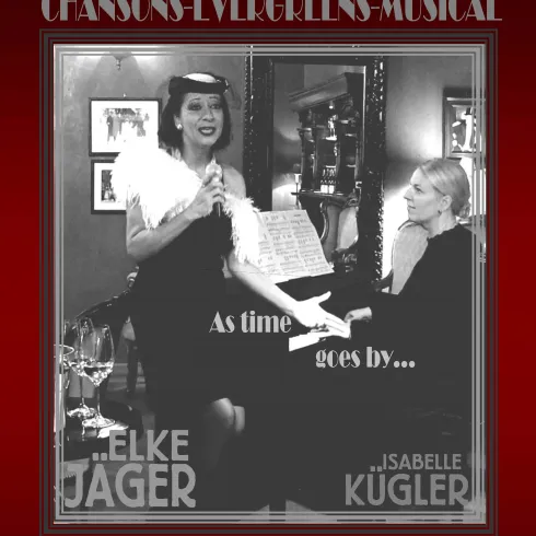 Zwei Frauen in eleganter Kleidung stehen auf einer Bühne. Eine singt mit Leidenschaft, während die andere am Klavier spielt.