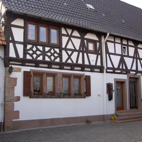 Ein traditionelles Fachwerkhaus mit markanten Fenstern und einer stilvollen Fassade. Die Steintreppe führt zur Eingangstür.