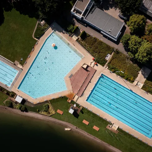Ein Schwimmbad mit drei Becken, umgeben von Grünflächen. Die Pools sind klar und einladend in der sonnigen Umgebung.
