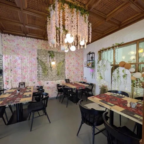 Ein schön dekoriertes Restaurant mit blühenden Wänden und stilvollen Möbeln. Die warmen Lichter schaffen eine einladende Atmosphäre.