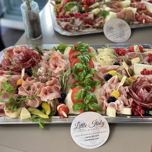 Eine ansprechende Platte mit verschiedenen Wurst- und Käsesorten, garniert mit frischen Kräutern und roten Beeren. Ideal für eine festliche Präsentation.