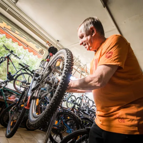 Werkstattmeister Heinen repariert ein Fahrrad in seiner Werkstatt.