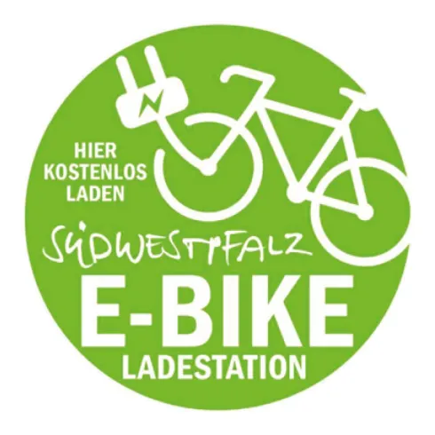 Ein grünes Logo für eine E-Bike-Ladestation. Es zeigt ein Fahrrad mit einem Ladeanschluss und den Text "Hier kostenlos laden" sowie "Südwestpfalz".