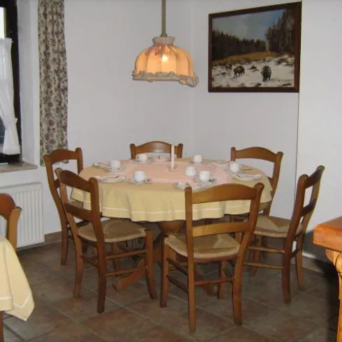 Ein Gastraum mit einem runden, bedeckten Tisch und Stühlen.