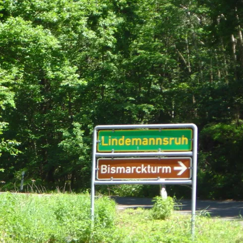 Im Hintergrund ist Wald und im Vordergrund sind zwei Verkehrsschilder übereinanader.