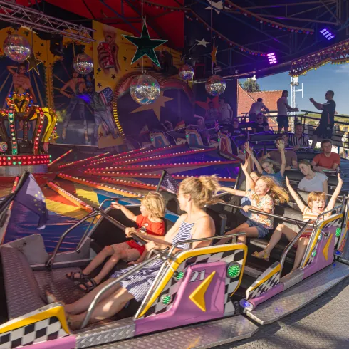 Ein bunter Jahrmarkt mit fröhlichen Fahrgästen in einem Karussell. Kinder und Erwachsene lachen und genießen die Fahrt.