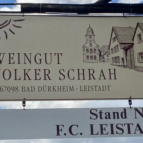 Ein Schild mit der Aufschrift "Weingut Volker Schrah" in Bad Dürkheim-Leistadt. Darunter steht "Stand Nr. 8 F.C. Leistadt".