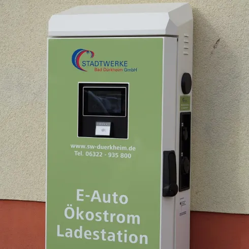 Eine Ladestation für Elektroautos mit Informationen zur Ökostromnutzung. Die Station ist in einem hellen Design gehalten und bietet kontaktierte Anleitungen zur Nutzung.