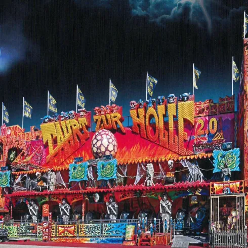 Ein lebhaftes Fahrgeschäft mit bunten Lichtern und gruseligen Dekorationen. Die Attraktion trägt den Namen "ZUR HÖLLE 2.0" und steht unter einem dunklen, mondbestrahlten Himmel.