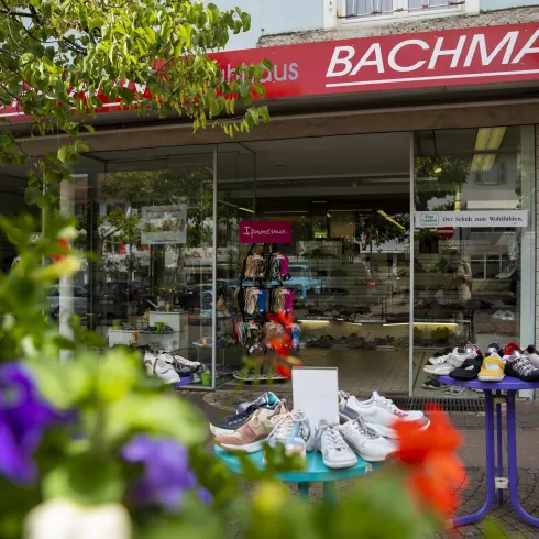 Ein Schuhgeschäft mit dem Namen "Bachmann". Vor dem Laden stehen verschiedene Schuhe auf einem Tisch.