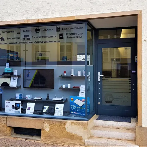 Ein Geschäft mit einer großen Schaufensterfront. Im Fenster sind verschiedene Produkte und Informationen sichtbar.