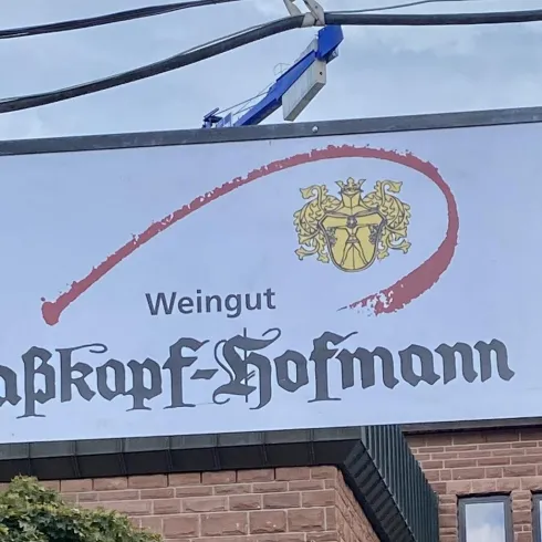 Ein Schild für das Weingut Raßkopf-Hofmann. Es zeigt die Hausnummer 20 und den Hinweis auf eigenen Ausschank.