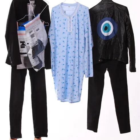 Drei verschiedene Outfits hängen an Kleiderbügeln. Dazu gehören eine blaue Nachthemd, eine schwarze Lederjacke und eine schwarze Hose.