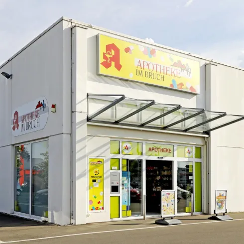 Ein modernes Geschäft mit einer großen Fensterfront und bunten Schildern. Vor dem Ladenparkplatz ist viel Platz.