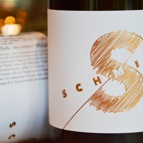 Eine Flasche Wein mit dem Etikett „SCHMITT“. Das Design zeigt einen künstlerischen Buchstaben „S“ in Gold und einfachen Text.