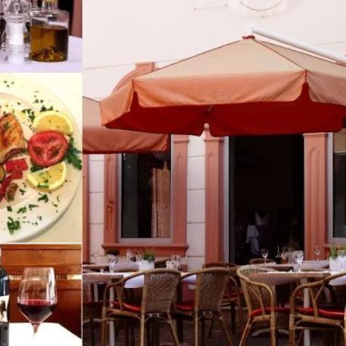 Ein einladendes Restaurant mit einem großen Sonnenschirm und Tischen im Freien. Auf dem Tisch stehen Weingläser und eine Vielzahl von Gerichten, darunter ein buntes Gemüsegericht.