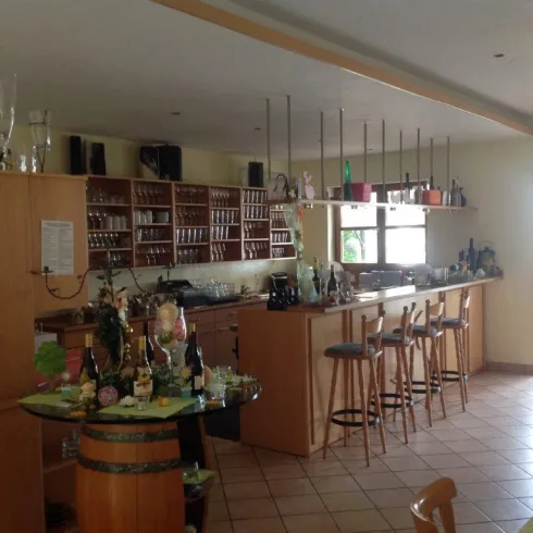 Eine gemütliche Bar mit Holzregalen und vielen Getränken. Helle Räume und Sitzplätze laden zum Verweilen ein.