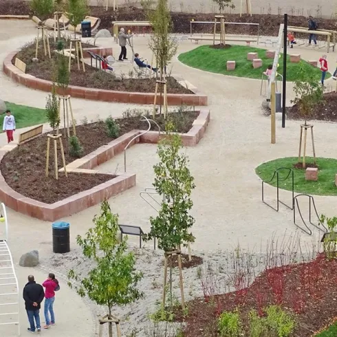 Ein moderner Spielplatz mit geschwungenen Wegen und verschiedenen Grünflächen. Besucher genießen die Freizeitaktivitäten in dieser einladenden Umgebung.