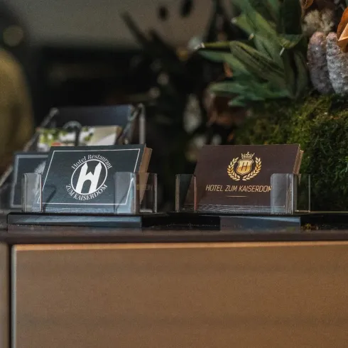 Ein Empfangstresen mit verschiedenen Visitenkarten. Im Hintergrund sind dekorative Pflanzen und eine ansprechende Gestaltung zu sehen.