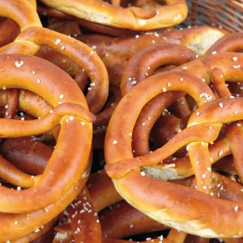 Eine Auswahl von frisch gebackenen Brezeln in einem Korb. Die Brezeln sind goldbraun und mit grobem Salz bestreut.