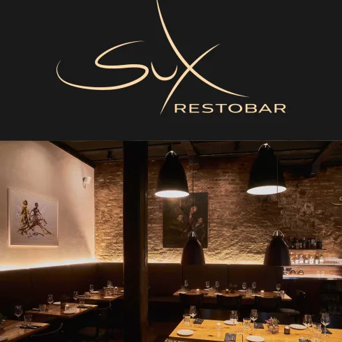 Ein stilvolles Restaurant mit schicker Beleuchtung und rustikalen Wänden. Die Tische sind elegant eingedeckt und schaffen eine einladende Atmosphäre.