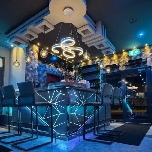 Eine stilvolle Bar mit modernen Lichtakzenten und eleganten Stühlen. Die Atmosphäre ist einladend und gemütlich.