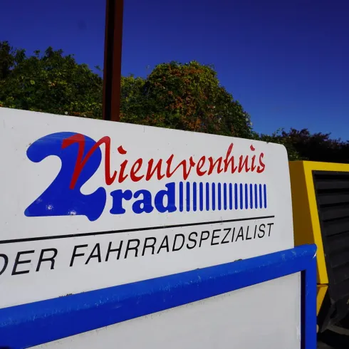 Ein Schild mit dem Namen "Nieuwvenhuis Rad". Darunter steht "DER FAHRRADSPEZIALIST".