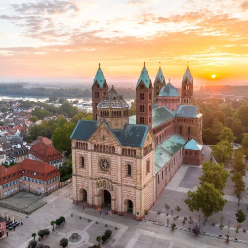 Eine beeindruckende Kathedrale mit markanten Türmen und einer schönen Fassade. Der Sonnenuntergang verleiht der Szene eine warme, goldene Lichtstimmung.