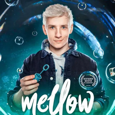 Ein junger Mann präsentiert ein Zaubertrick-Set mit Seifenblasen. Der Hintergrund zeigt eine mystische Atmosphäre mit Blasen und leuchtenden Effekten.