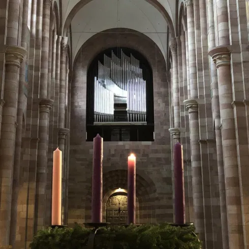 Eine beeindruckende Orgel mit vielen metallischen Pfeifen ist im Vordergrund zu sehen. Im Hintergrund erstreckt sich der große Raum einer Kirche.